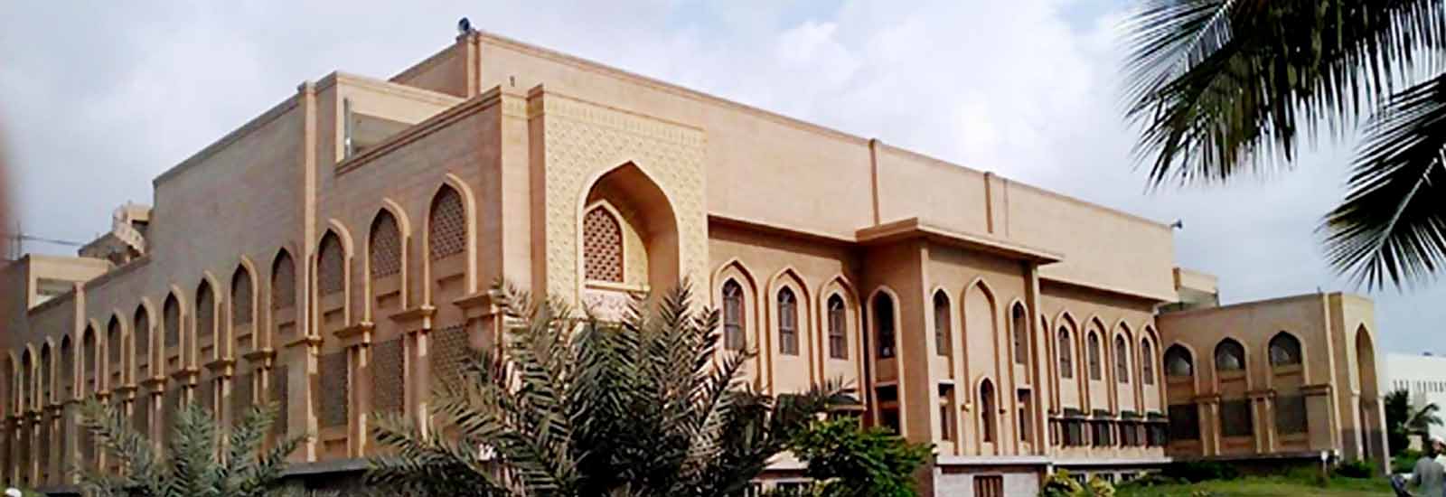 exterior view of a building with Islamic architectural design featuring arched windows and decorative patterns, with palm trees in the foreground