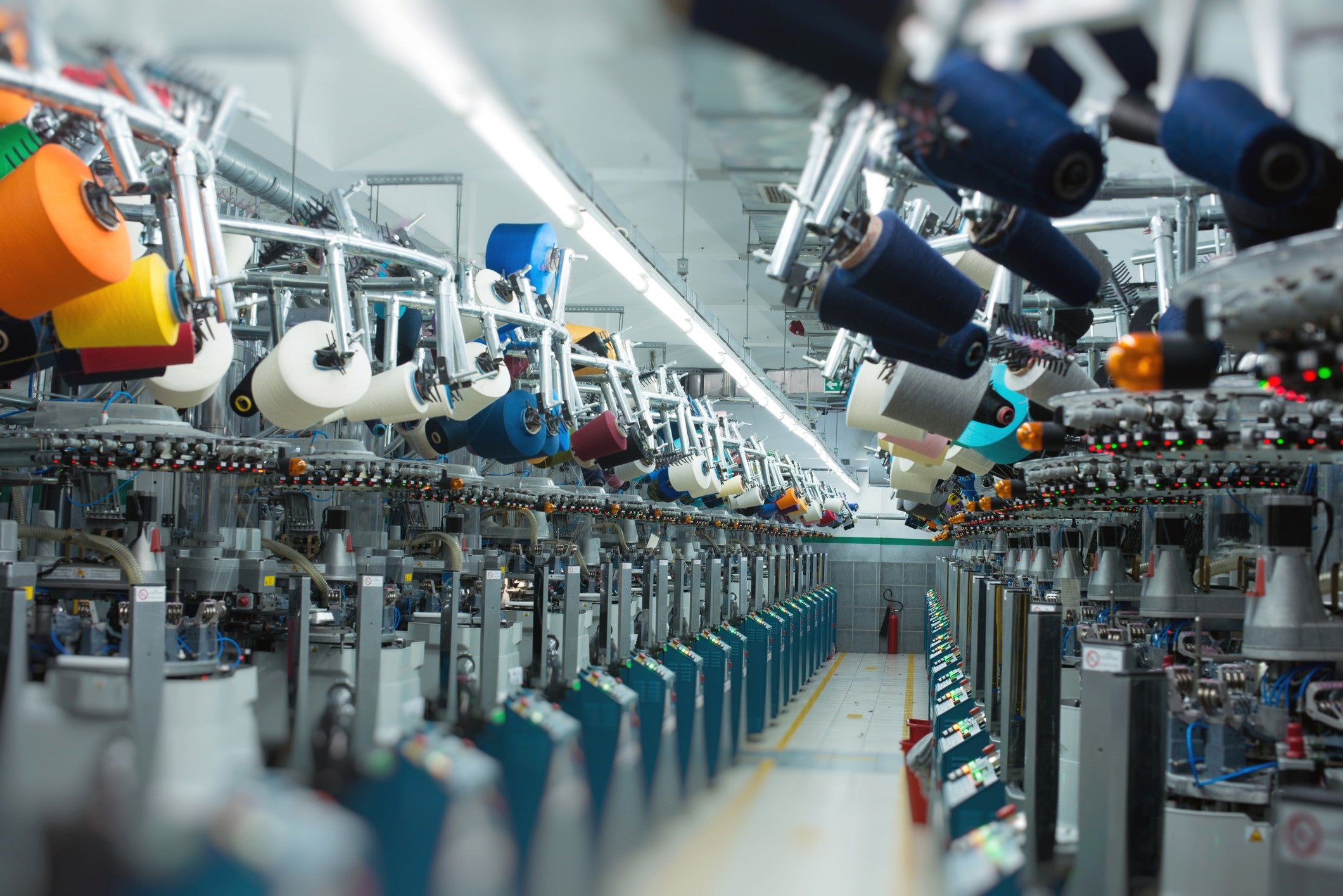 modern textile manufacturing factory with rows of automated knitting machines and colorful yarn spools