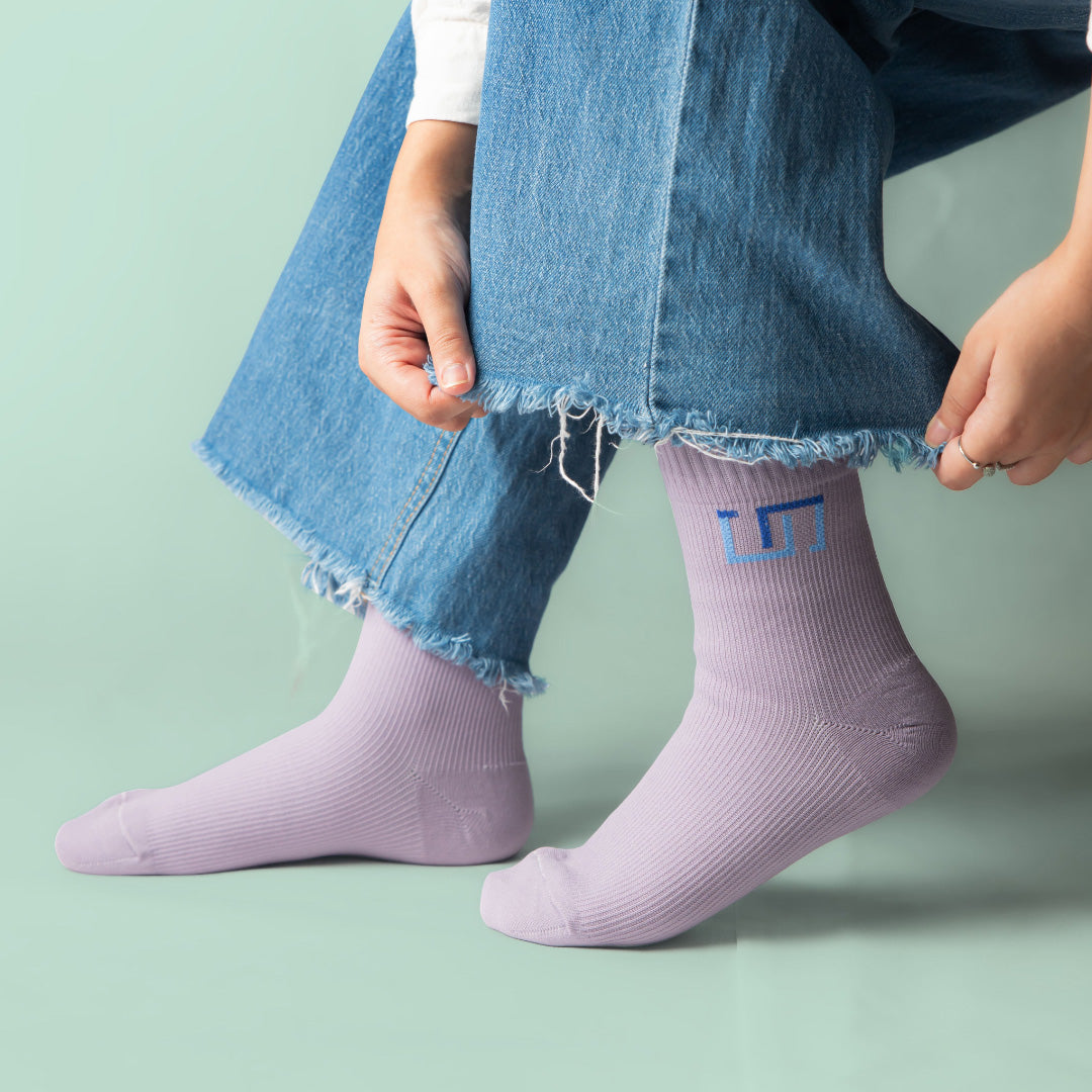 woman wearing soft lilac socks sitting on a light green background
