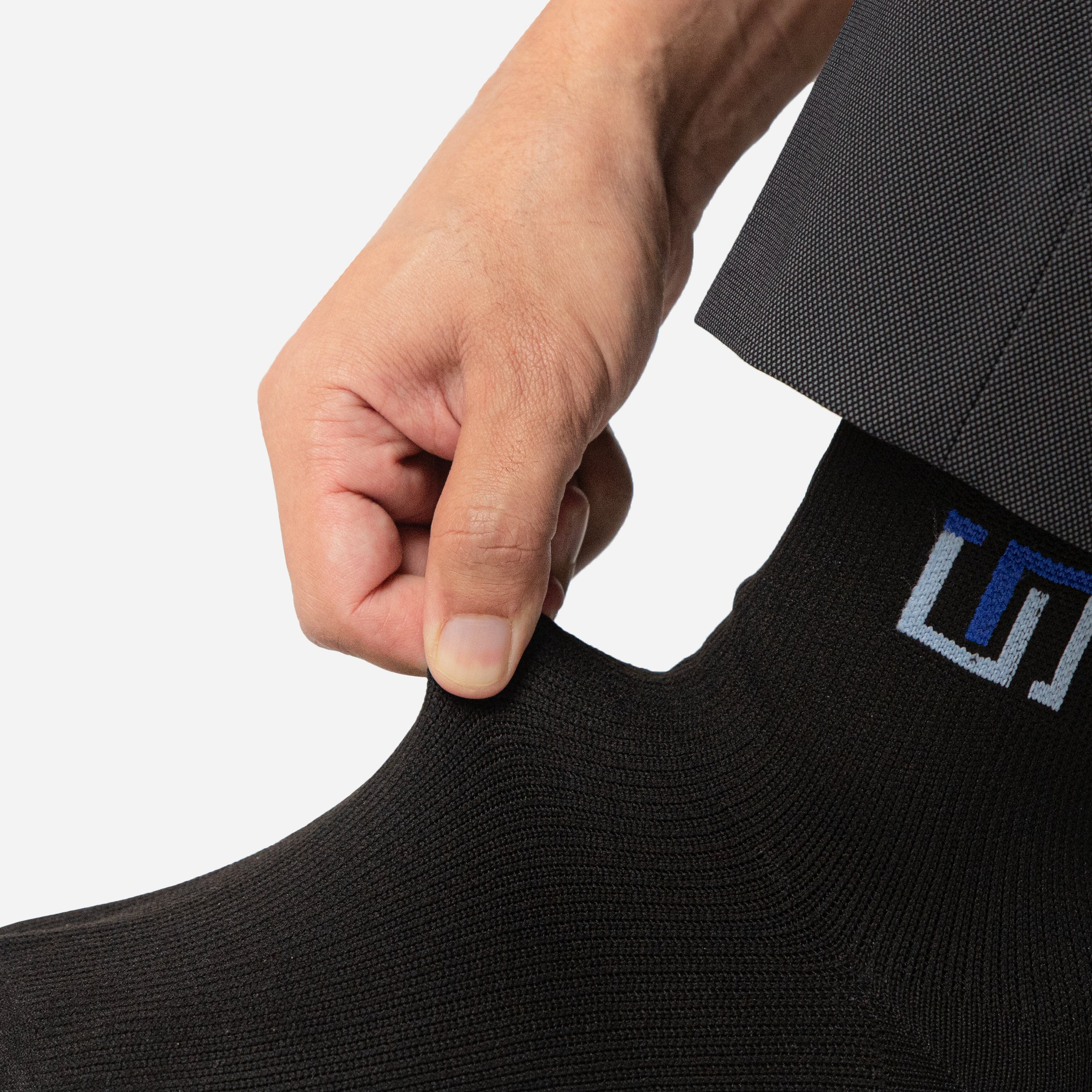 a person checking the material quality of wudhu socks by stretching it