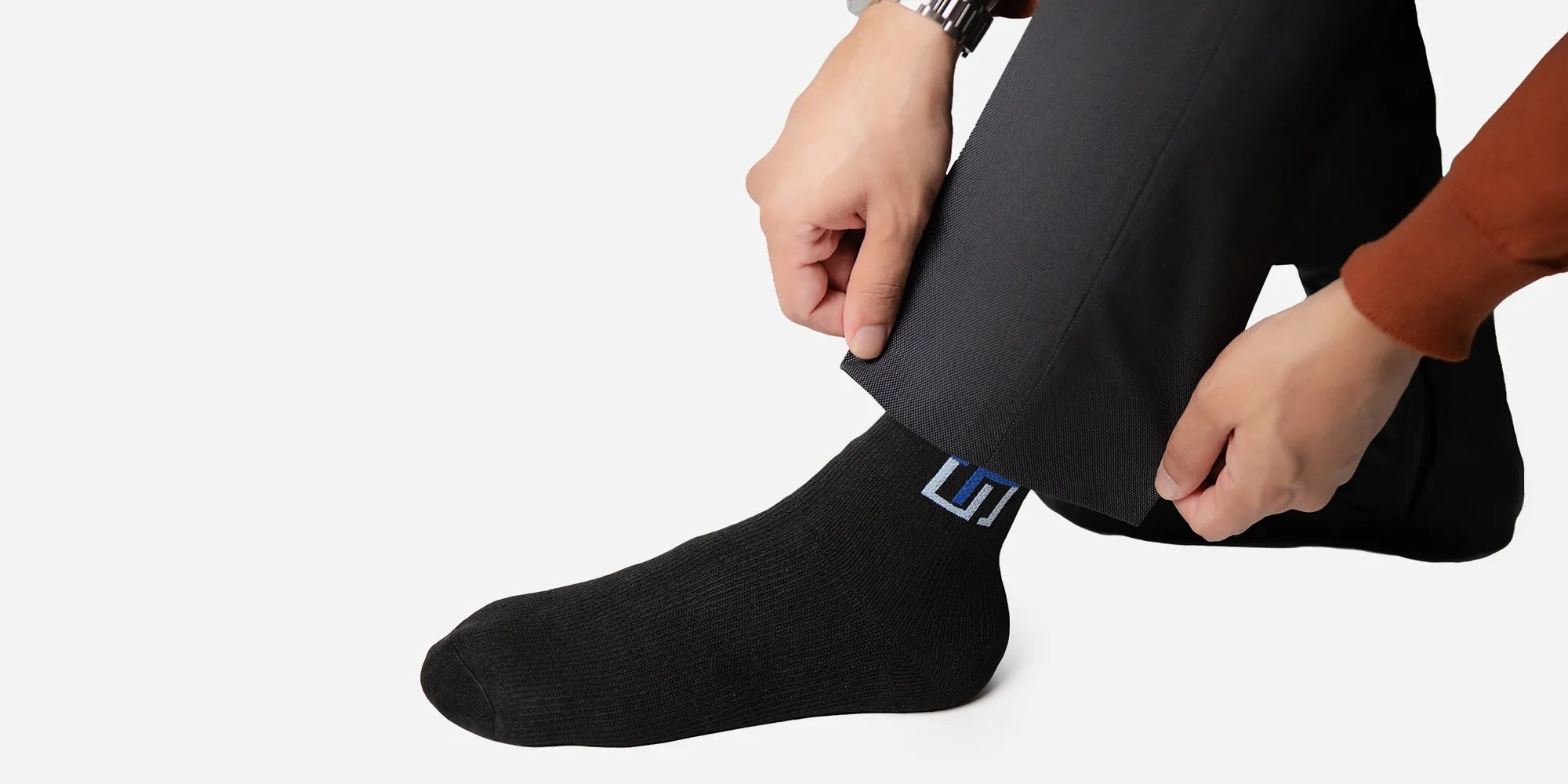 A man wearing black wudhu socks with a logo of The Wudhu Socks on it