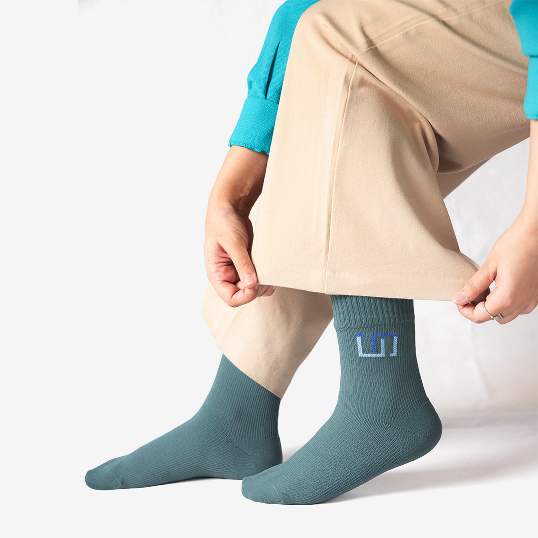 a woman adjusting teal blue wudhu socks