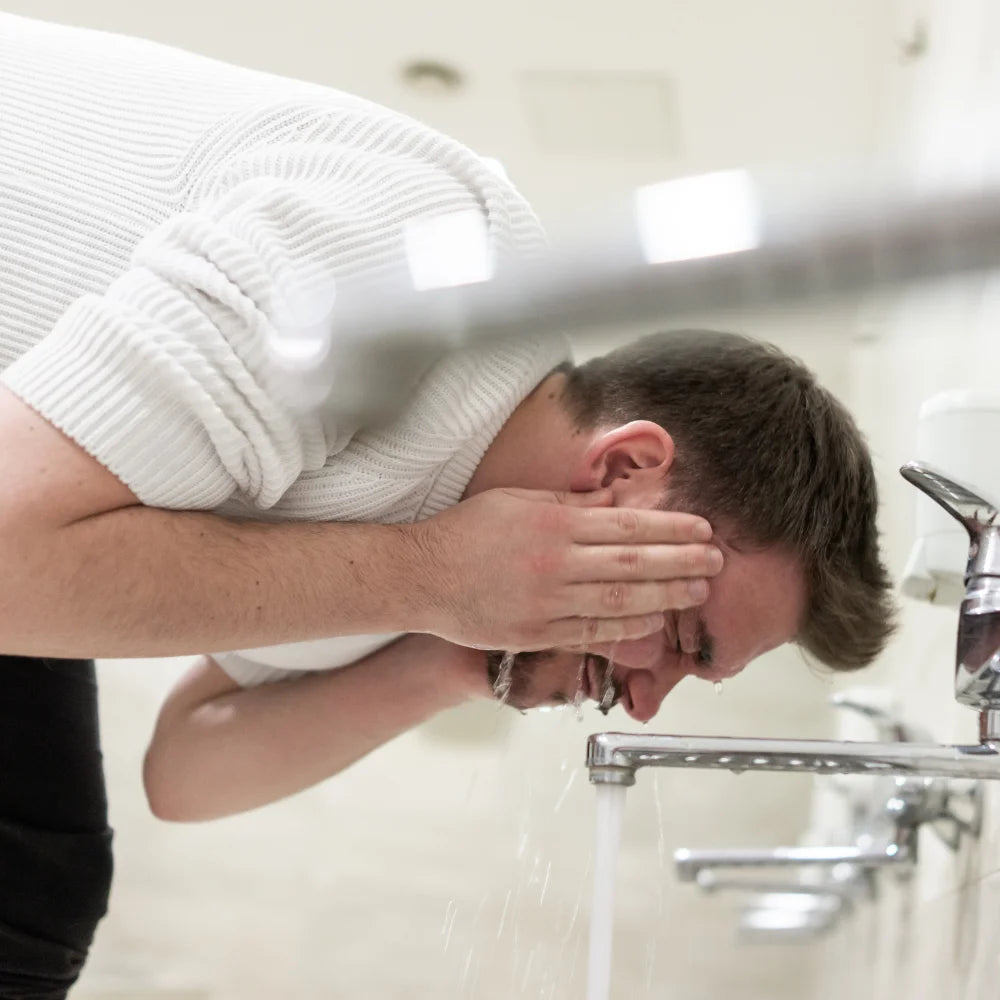 a man doing wudhu from water flowing out of a tap