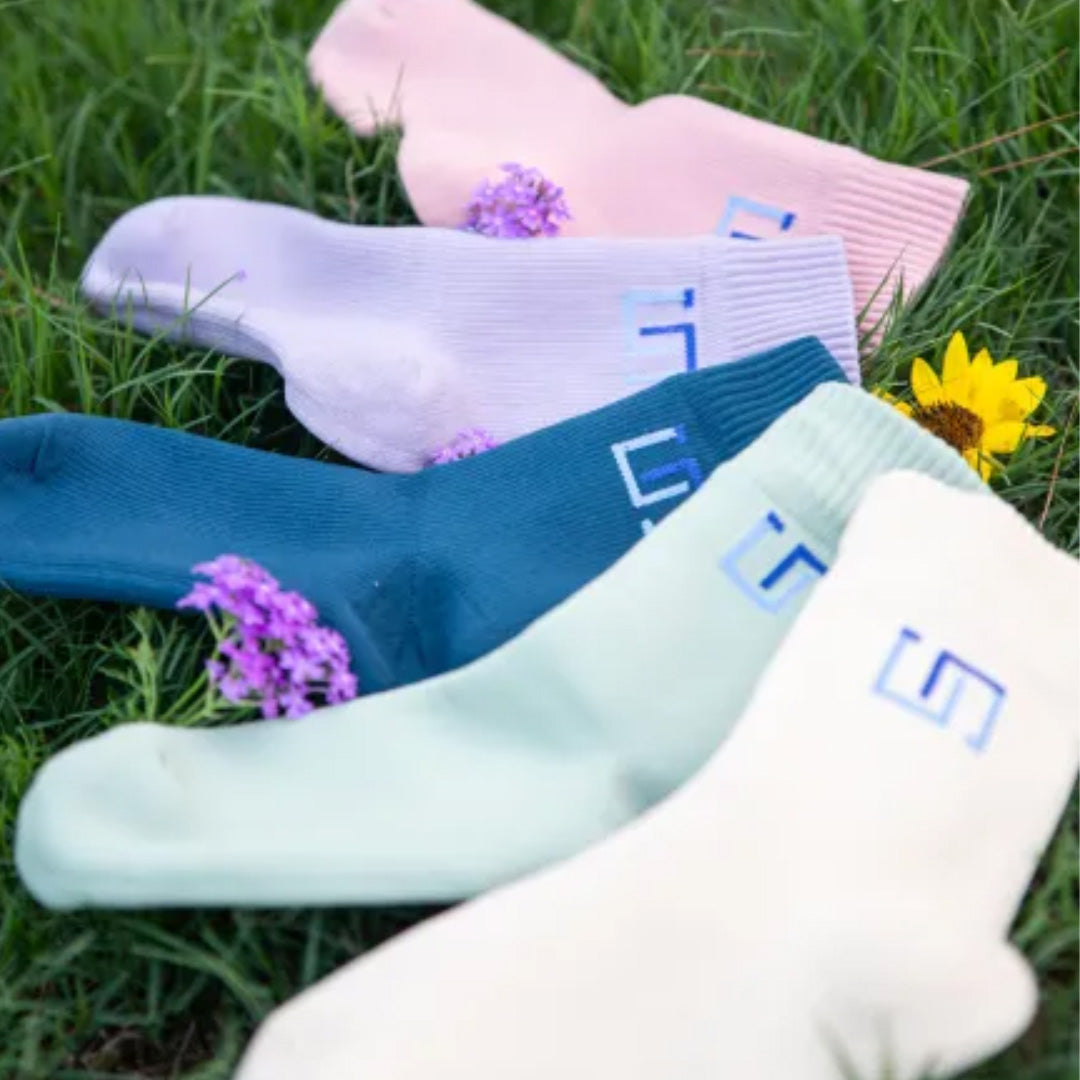 five pairs of socks in different colors on grass
