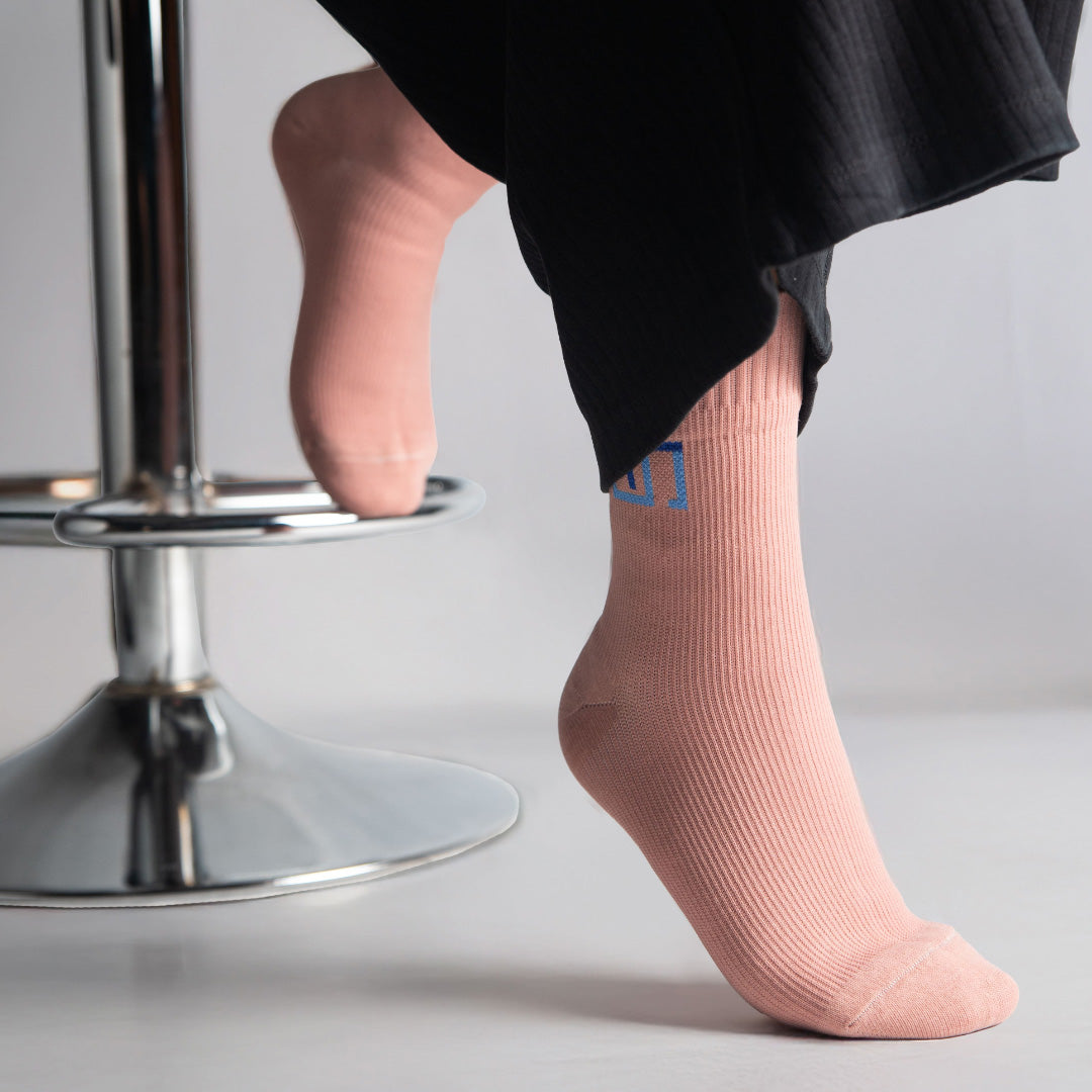 woman wearing tea pink socks sitting on a black stool