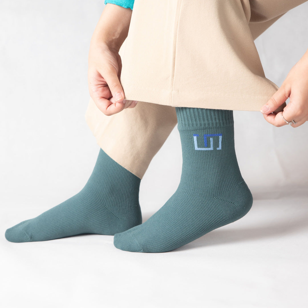 woman wearing teal blue socks on a light gray background
